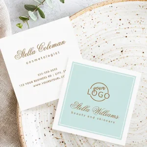 Square business card with a soft pastel-aqua background, framed by a thin double white rectangular border. It has a custom logo at the top center. Below the logo, a name is printed in a sophisticated calligraphic script font, with a tagline in a clean lowercase sans-serif font directly beneath it.