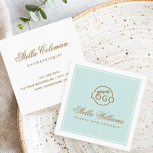Square business card with a soft pastel-aqua background, framed by a thin double white rectangular border. It has a custom logo at the top center. Below the logo, a name is printed in a sophisticated calligraphic script font, with a tagline in a clean lowercase sans-serif font directly beneath it.