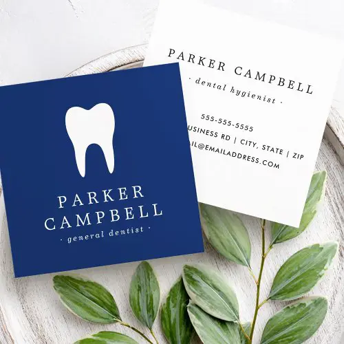 A square business card for a dentist. One view has a navy blue background with a white tooth icon and customizable name in white text. The other view has a white background with centered contact information including a phone number and address in black text.