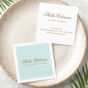 A square business card showing front and back. The front features a light aqua blue central panel with a thick white border, defined by a thin aqua outline. It contains gold-brown script name text above all-caps sans-serif tagline text. The back is white with organized contact details and repeating script name.