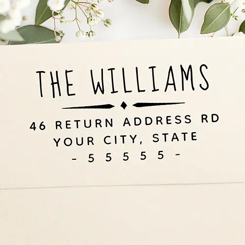 Rubber stamp featuring a hand-lettered custom family surname header, a central, vintage style diamond divider line, and structured address and zip code text lines at the bottom.