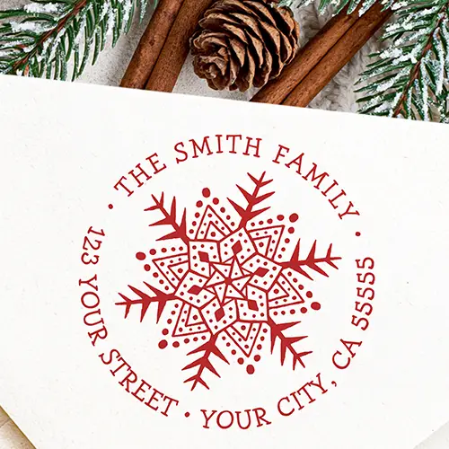 Round rubber stamp design featuring a central hand-drawn mandala snowflake illustration encircled by arched typewriter-style custom name and address text.