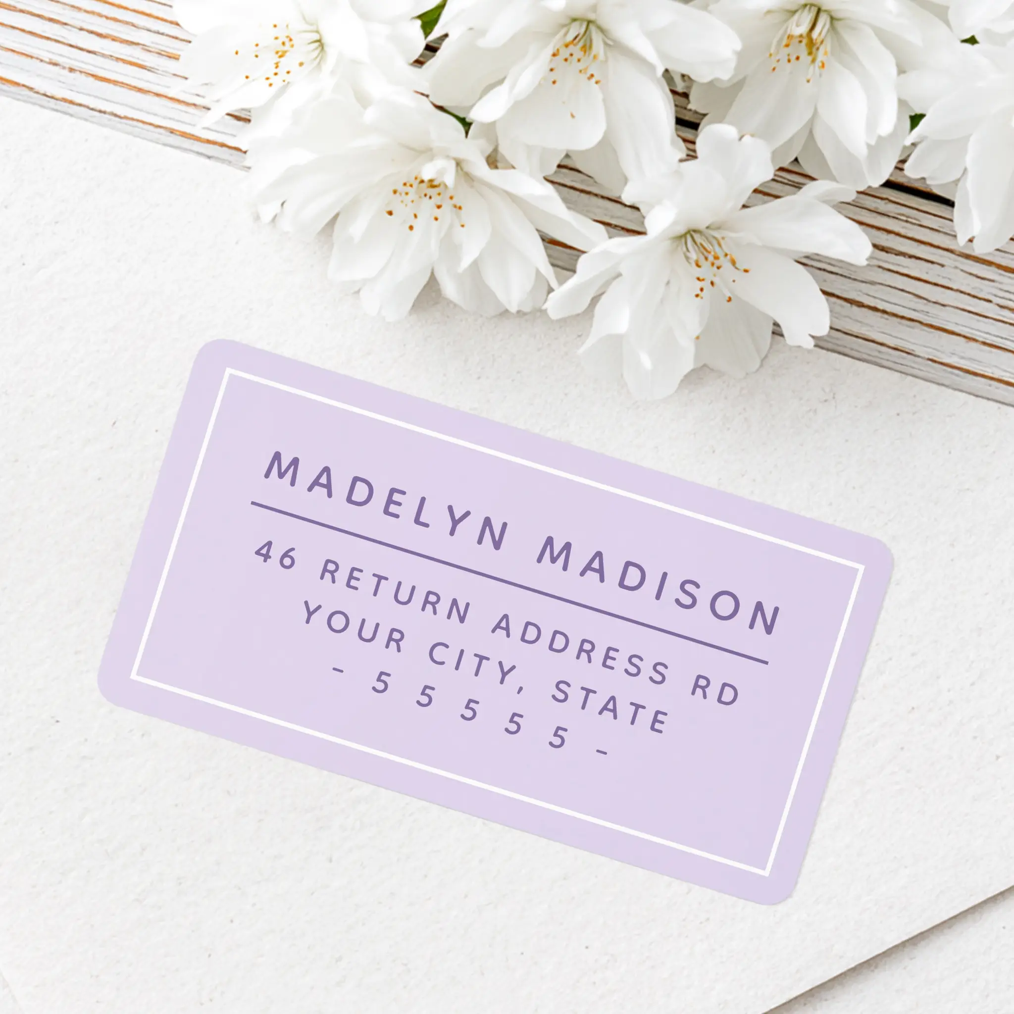 Horizontal rectangular light purple address sticker featuring a white inner border frame and centered purple sans-serif text for name, street address, and zip code.