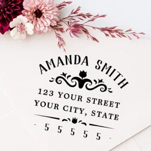Custom rubber stamp design featuring an arched uppercase name, a central scrollwork tulip floral flourish divider, two straight address lines, and a spaced ZIP code line framed with dashes.