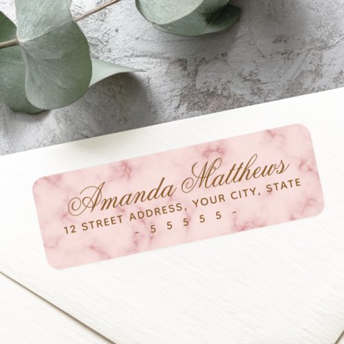 A rectangular return address label with rounded corners. The background features a pink marble texture with rose-colored veining. The text includes a large elegant script name in gold-brown ink with a clean block address below.