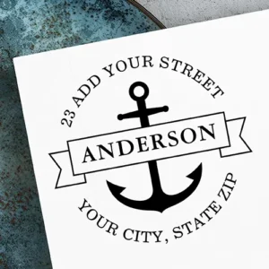 Round stamp design featuring a central ship anchor graphic layered behind a horizontal name banner, encircled by arched street, city, state, and zip code text in a serif font.