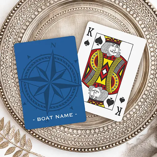 Playing cards featuring a large, tonal dark blue compass rose surrounded by a rope border and customizable text along the bottom edge on a deep blue background.
