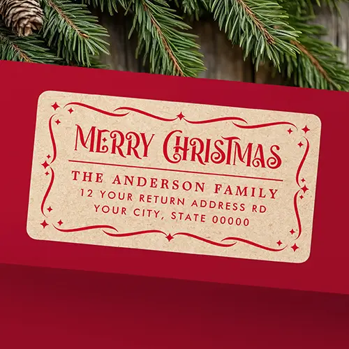 A rectangular self-adhesive return address label with printed light brown kraft paper background with rich red text and ornamental frame. The top displays a decorative "Merry Christmas" header with flourishing serifs, a horizontal divider, and three lines of custom family name and address text inside an ornate star-accented scroll border.