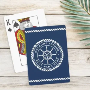 Playing cards featuring a deep navy blue background with white rope borders at the top and bottom. A central circular rope medallion contains a white ship's steering wheel. Curved customizable text reads "WELCOME ABOARD" above the wheel with more customizable text, for example a boat name, below it.