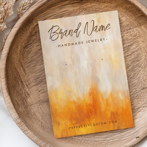 Custom earring display card with abstract painted background in orange, beige, and gold tones - warm autumn colors