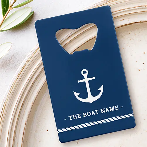 Flat rectangular navy blue metal credit card bottle opener featuring a top opener cutout, a white central anchor icon, custom boat name text, and a white twisted rope bottom border.