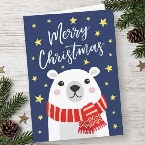 Vertical folded Christmas card showing an illustrated white polar bear with a red scarf against a starry navy blue background on the front, and a custom holiday message on the white interior.