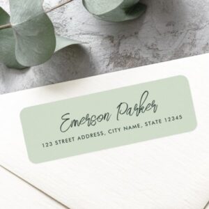 A rectangular, rounded-corner sticker in a light sage green color with dark charcoal elegant script name text above a dark block text address. Perfect for wedding envelopes and stationery. This shows a personalized return address label with elegant design.