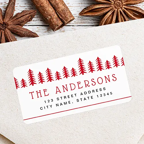 Rectangular white return address sticker featuring a top row of red pine tree illustrations above a custom red family name, black address lines, and a thin red bottom border line.