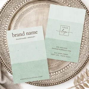 A vertical earring display card featuring three shades of pastel sage green with brown brand text at the top and two green guide dots in the center.