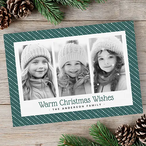 Horizontal Christmas card featuring a dark green border with diagonal white dotted stripes framing three vertical family photos and green Warm Christmas Wishes text.
