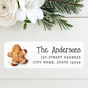 Horizontal rectangular return address label featuring a watercolor gingerbread cookie illustration on the left and a playful script family name above two lines of address text on the right.