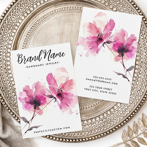 A vertical earring holder card featuring pink messy watercolor style blossoms at the bottom, black script text at the top, and subtle guide marks for punching earring holes.