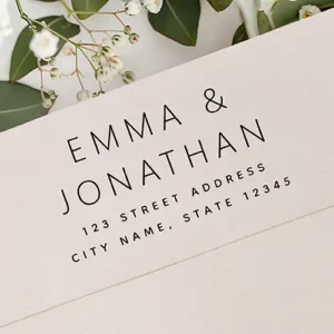 Custom rubber stamp design displaying stacked couple first names in a clean, light sans-serif font with spaced address text lines below.