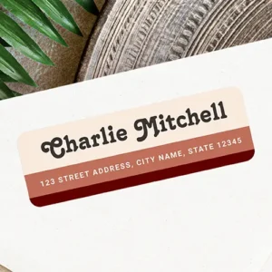 Horizontal self-adhesive label with cream, rust, and burgundy-brown color blocks, featuring dark charcoal groovy serif typography above a white sans-serif address line.