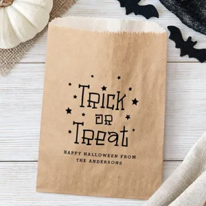 A brown kraft paper favor bag printed with the black text Trick or Treat surrounded by small stars, above "Happy Halloween From" and your custom name.