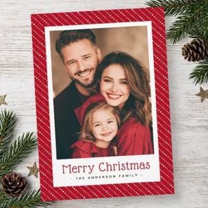 Vertical Christmas card featuring a red background with diagonal white dotted pinstripes framing a family picture in a white border with red Merry Christmas text below.