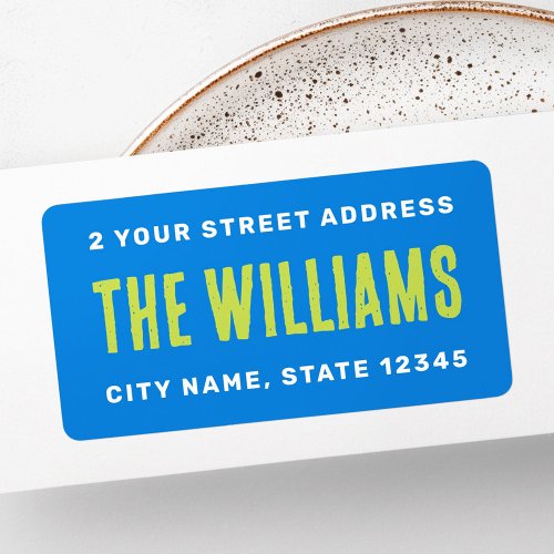 Personalized rectangular return address label with blue background, green family name, and white address text.
