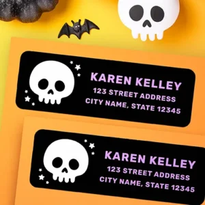 A black horizontal rectangular address sticker with rounded corners. On the left is a white cartoon skull graphic surrounded by tiny white stars. On the right are three lines of customizable lavender purple text for a name, street address, and city, state, and zip code.