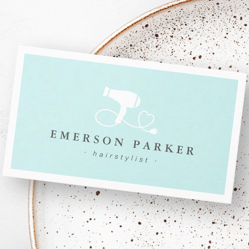 Modern hairstylist business card design featuring pastel aqua background, white hair dryer with heart cord icon, and clean typography. Professional customizable template for salons and beauty professionals.