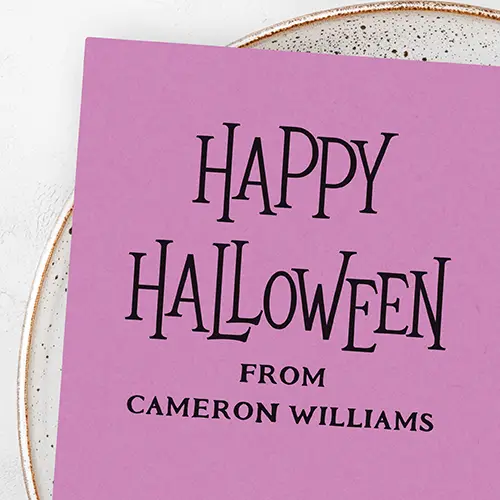 A square Halloween rubber stamp. The top section reads "HAPPY HALLOWEEN" in a tall, stylized gothic serif font, followed by "FROM" and a customizable full name in spaced all-caps serif typeface below.
