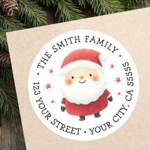 Round Santa Claus return address label with watercolor Santa in red suit, fluffy beard, and rosy cheeks. Surrounded by red stars, customizable family name and address in serif font. Perfect for Christmas cards, holiday invitations, and festive gift mail.
