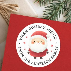 Round Christmas sticker featuring watercolor Santa Claus in red suit with fluffy beard and red stars. Customizable circular text reads “Warm Holiday Wishes” and your custom name. Perfect for sealing holiday cards, decorating gifts, and festive packaging.