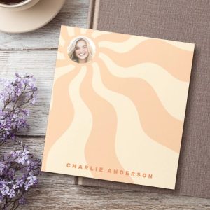 Custom retro notepad with orange and yellow sunburst rays, round photo frame at the top left, and personalized name text in bold orange letters at the bottom. Great for gifts