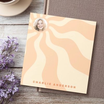 Custom retro notepad with orange and yellow sunburst rays, round photo frame at the top left, and personalized name text in bold orange letters at the bottom. Great for gifts