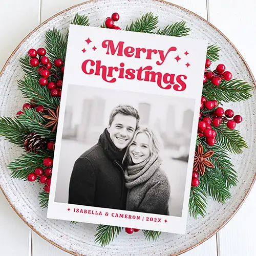 A vertical Christmas card featuring your custom photo. Above the photo is bold red 70s-style 'Merry Christmas' text with star icons. Below is personalized name text.