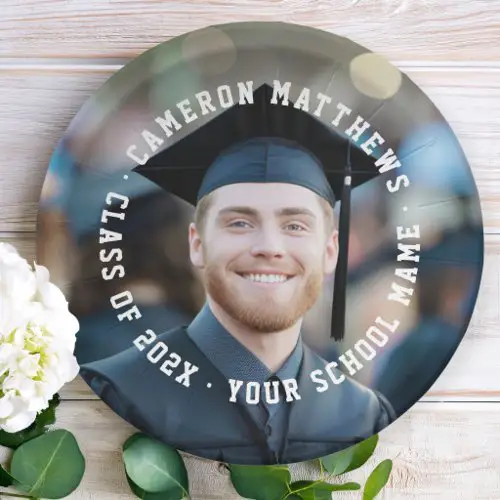 A round paper plate featuring a full-surface custom photo. A white circular text border frames the center with the graduate's name, year and school in a varsity style block font.