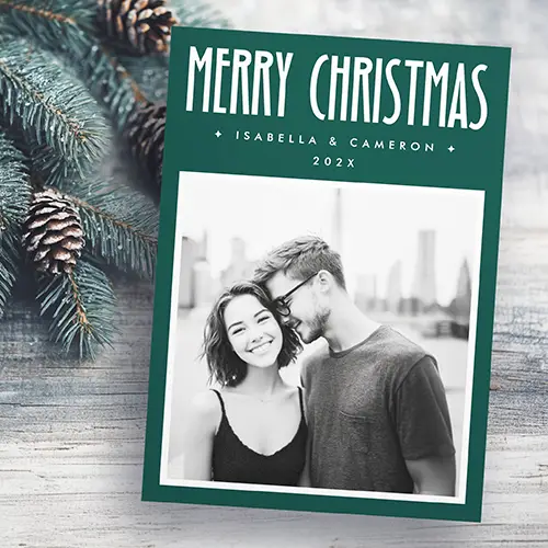 A vertical Christmas card featuring a deep forest green background. At the top, "MERRY CHRISTMAS" is written in tall white letters. Below, a placeholder for names and the year is flanked by two stars. The bottom has a large rectangular custom photo area with a thin white border.
