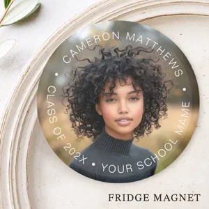 A round custom fridge magnet featuring a full-bleed rectangular custom photo slot. Arched white sans-serif text curves along the top border displaying the graduate's name, while the bottom border displays custom text for the graduation year and school name, separated by small dots.