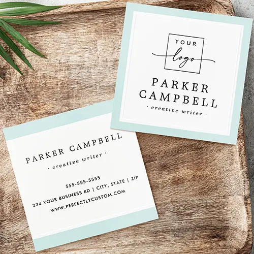 Front and back views of a square business card with an aqua blue and metallic design. The top card shows a white center with a custom logo placeholder and serif text, framed by a thin foil border and an outer light aqua blue band. The bottom card displays the back view, featuring horizontal aqua blue and real foil headers and footers framing centered contact information text blocks.