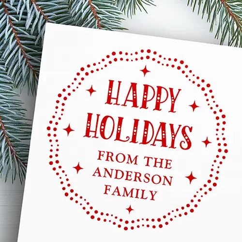 An ink rubber stamp featuring a circular wavy scalloped border made of double rows of dots, containing central text reading Happy Holidays in a dotted serif font above custom family name lines and four-point starburst symbols.