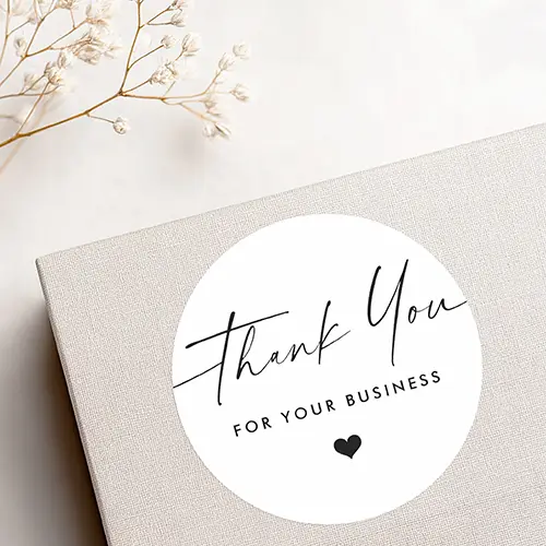 Business sticker featuring the words "Thank You" in an elegant black handwritten script font, followed by "FOR YOUR BUSINESS" in a clean, capitalized sans-serif font stack. A small solid black heart icon is centered directly beneath the text.