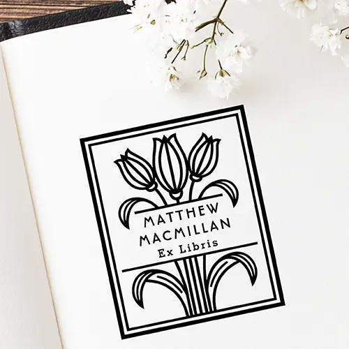 Rectangular wood-mounted rubber stamp featuring a geometric tulip illustration, double line border, and custom Ex Libris name typography. Vintage Art Deco style.