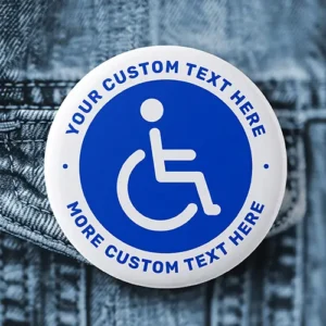Custom blue wheelchair symbol pin button badge. Round pin-back badge featuring a white wheelchair accessibility icon on a blue circular background, encircled by a white rim with custom arched blue text.