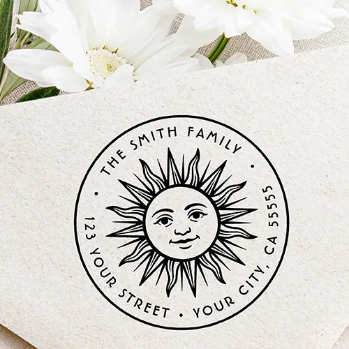 Round rubber stamp design featuring a central vintage sun face with radiant rays, surrounded by arched custom uppercase name and address text within a circular border.
