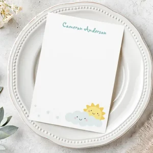 Vertical flat stationery sheet featuring a custom teal script name header and cute smiling sun, blue cloud, and star graphics in the lower corner.