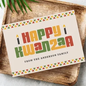 Custom Kwanzaa card with geometric triangle pattern and black candles A Kwanzaa card showing red, green, and yellow block lettering #Happy Kwanzaa", candle graphics, and geometric triangle border trim on a cream background.