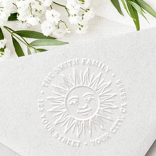A circular embosser design displaying a central celestial boho sun face surrounded by radial rays, with curved return address text around the border.
