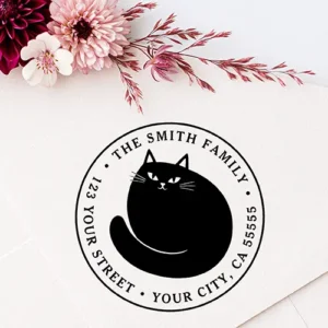 A circular rubber stamp artwork featuring a central silhouette of a curled black cat surrounded by custom name and address text rings.